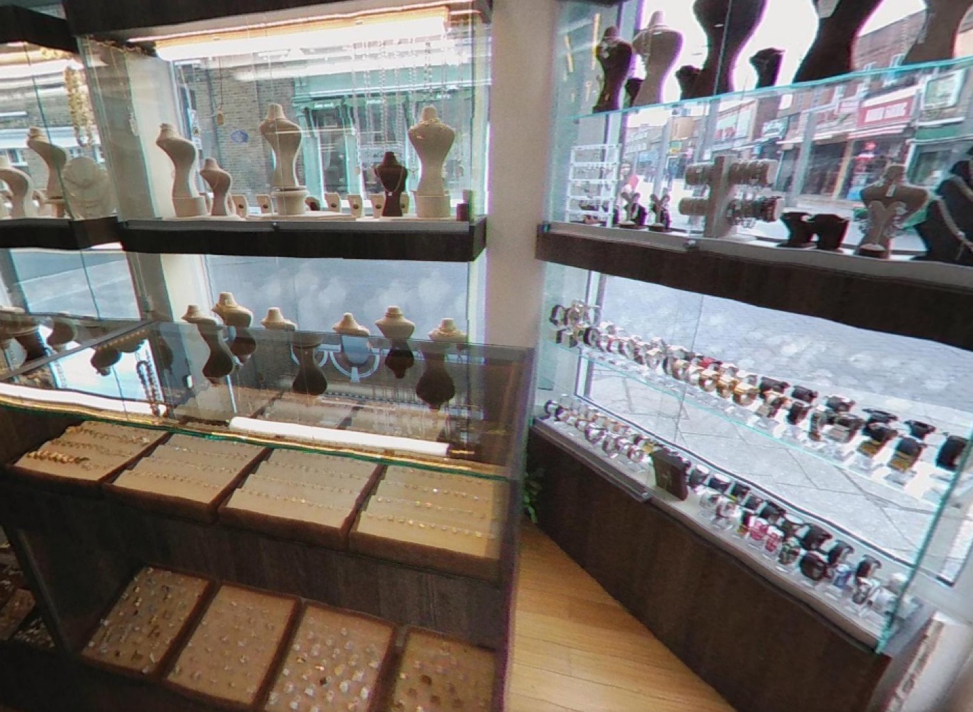 Display cabinets of necklaces and watches inside Italgold London, with Walthamstow High Street visible through the shop window